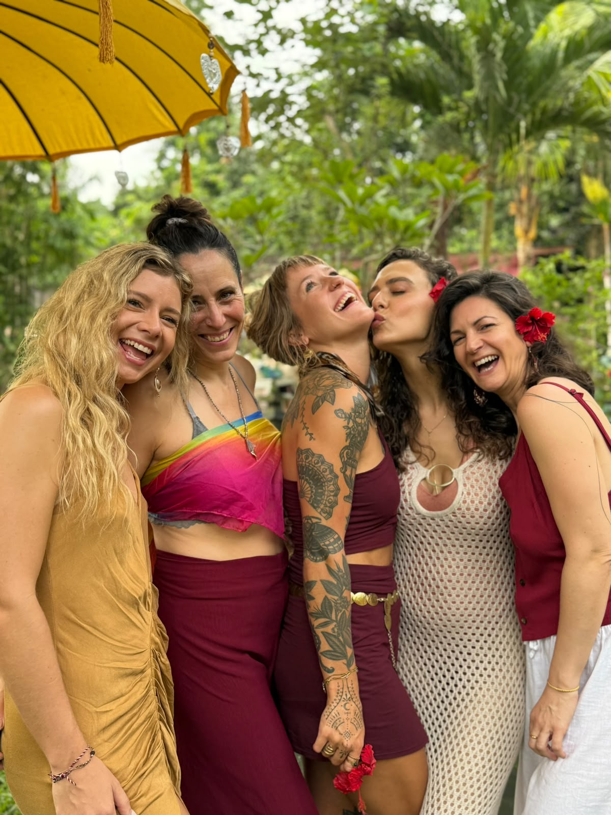 A laughing group under a yellow parasol in a tropical garden