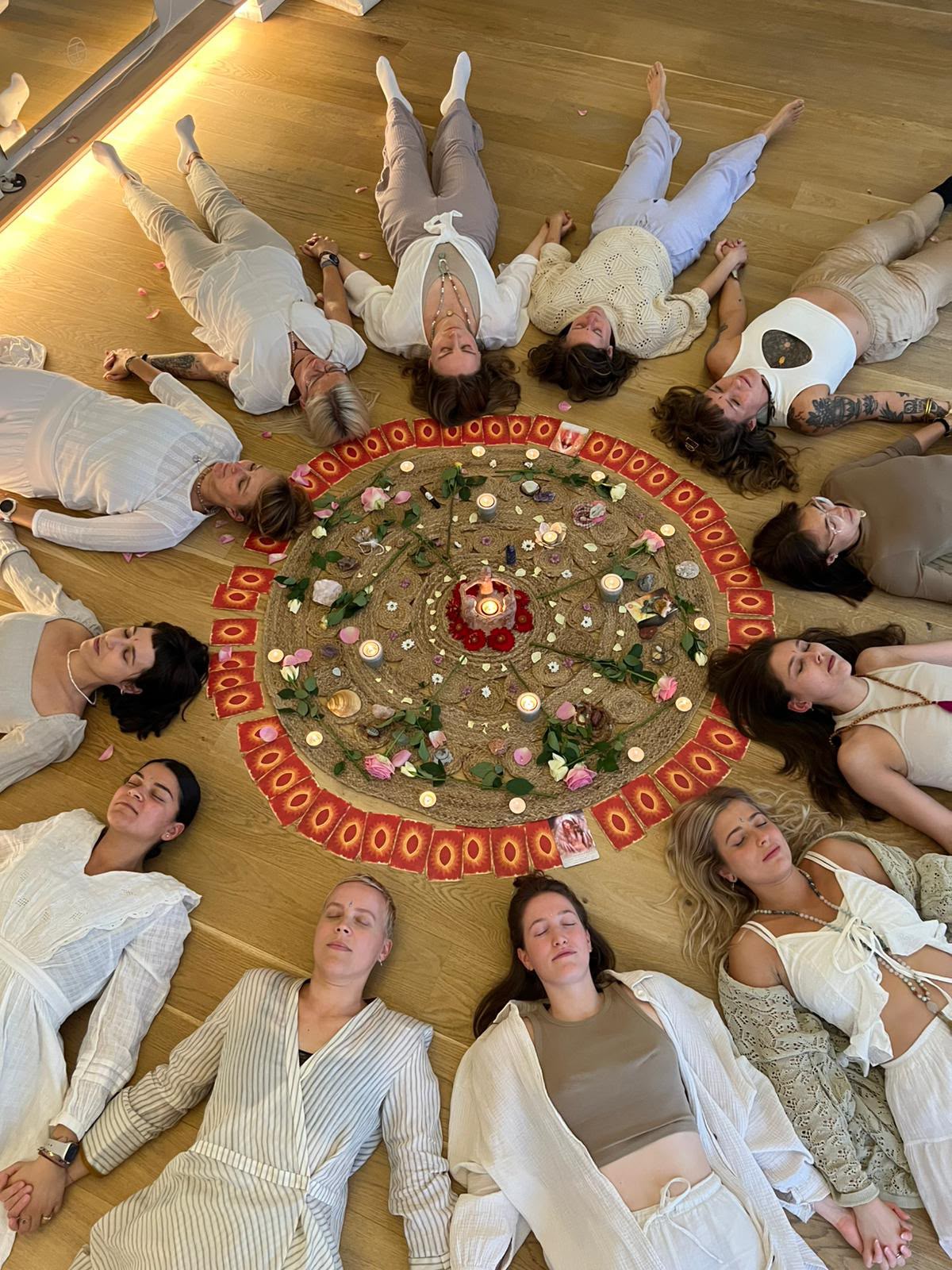 Participants lying in a circle around a candlelit flower mandala