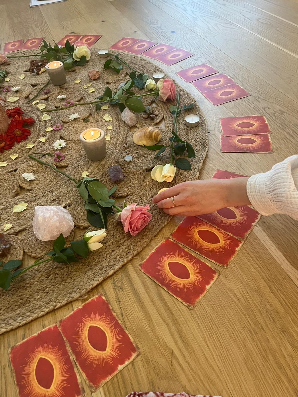 Hands laying an altar mandala of flowers, candles and cards